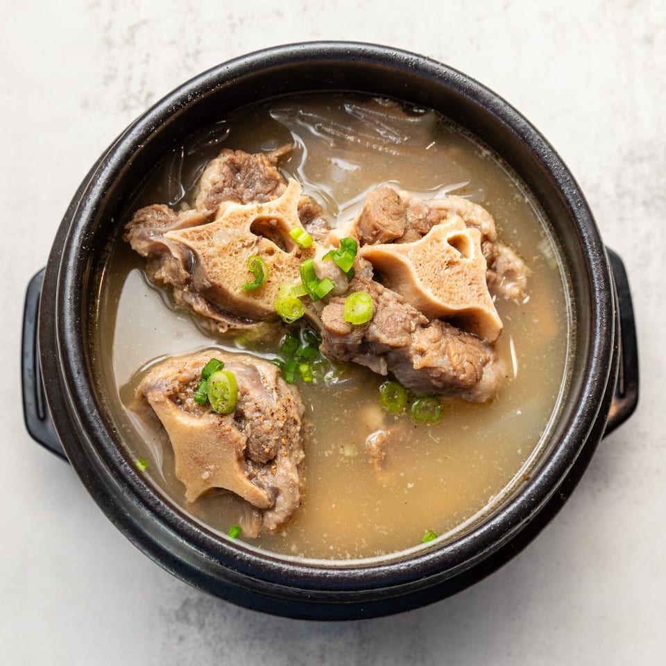 Naju Tofu's Korean oxtail soup, garnished with green onions, in a black stone bowl.